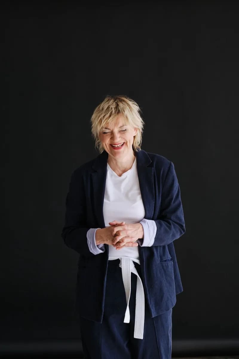 Anna Windmüller lehnt entspannt an einem Baum im Freien, warmer Blick, halbnahe Aufnahme im natürlichen Licht